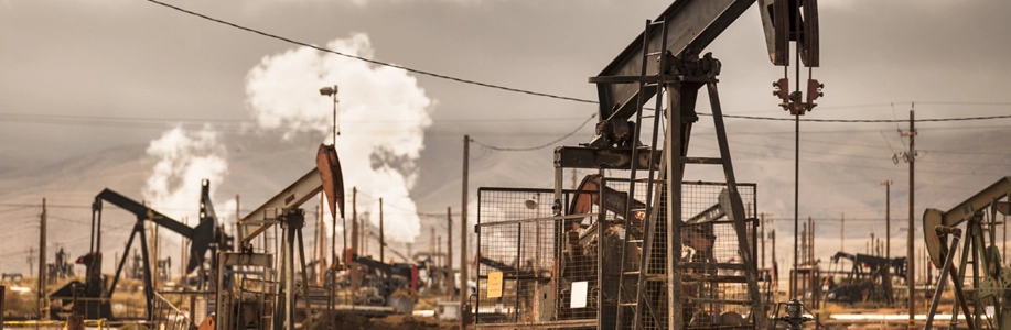 Oil derricks pump surrounded by smoke and haze