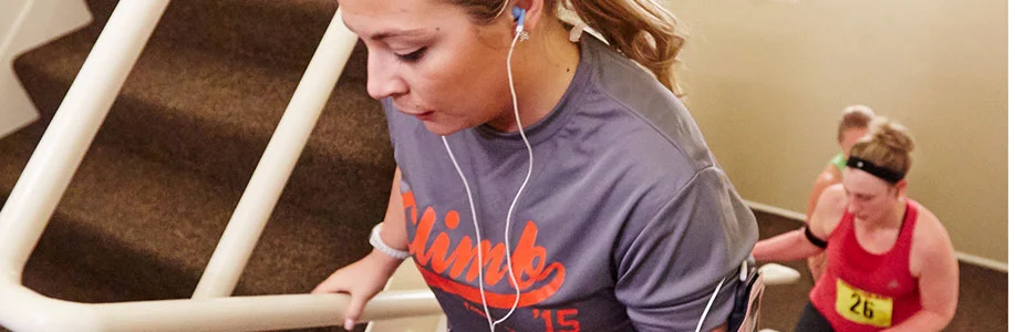 Woman climbs stairs in Fight For Air Climb shirt